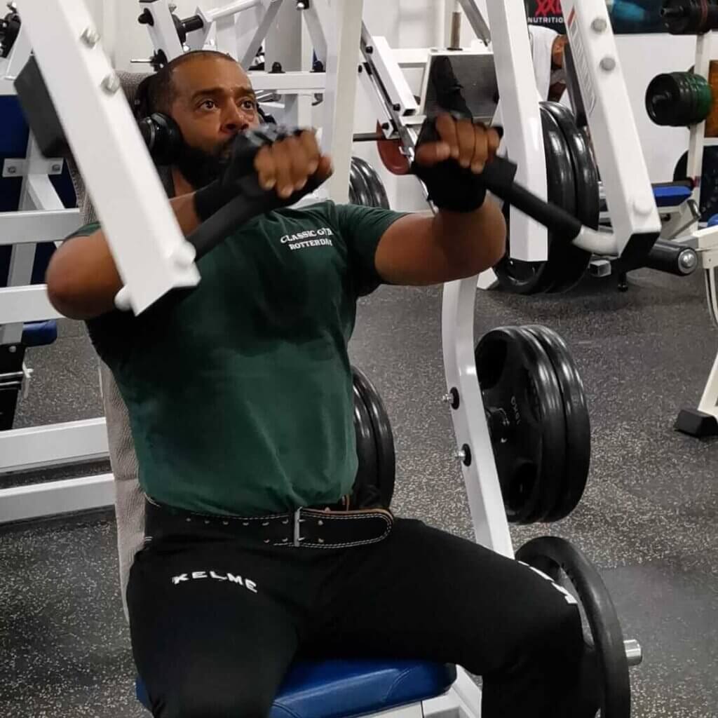 Man voert een incline chest press uit op een Hammer Strength free-loaded machine, gefocust op kracht en stabiliteit.