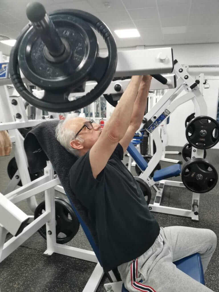 Een 65-plusser traint borstspieren met de incline press machine van Hammer Strength