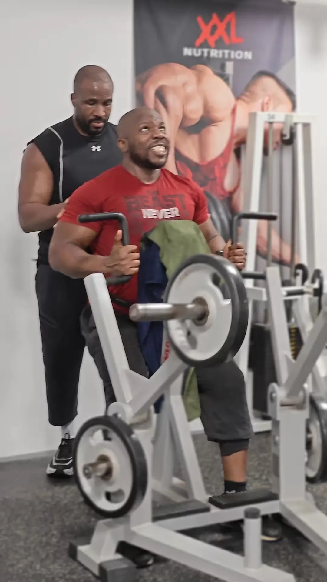 Atleet doet low row op P&A‑machine met ondersteuning van gymbro in Classic Gym Rotterdam